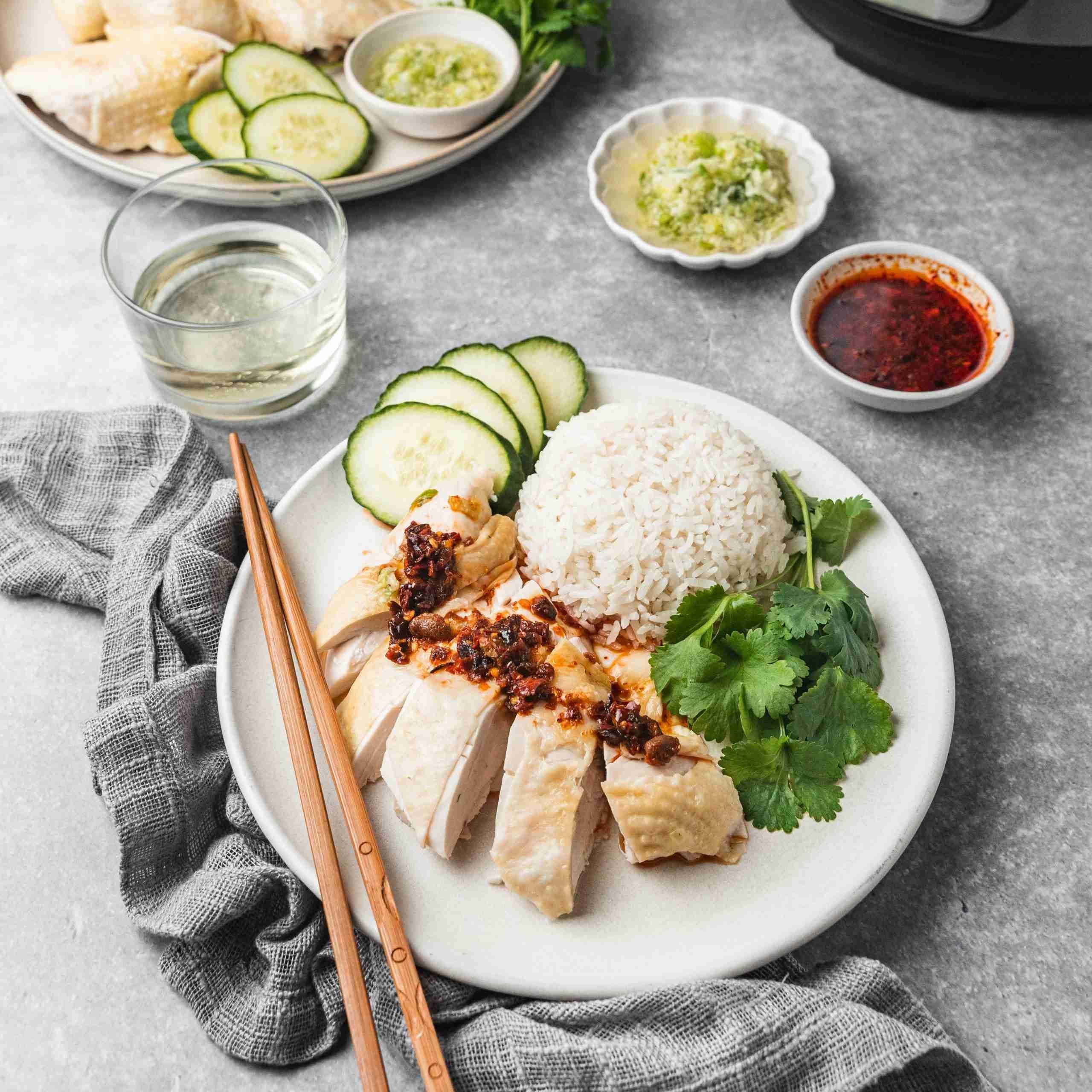 Chicken & Rice On Plate Served With Sauce Tubs And Chopsticks